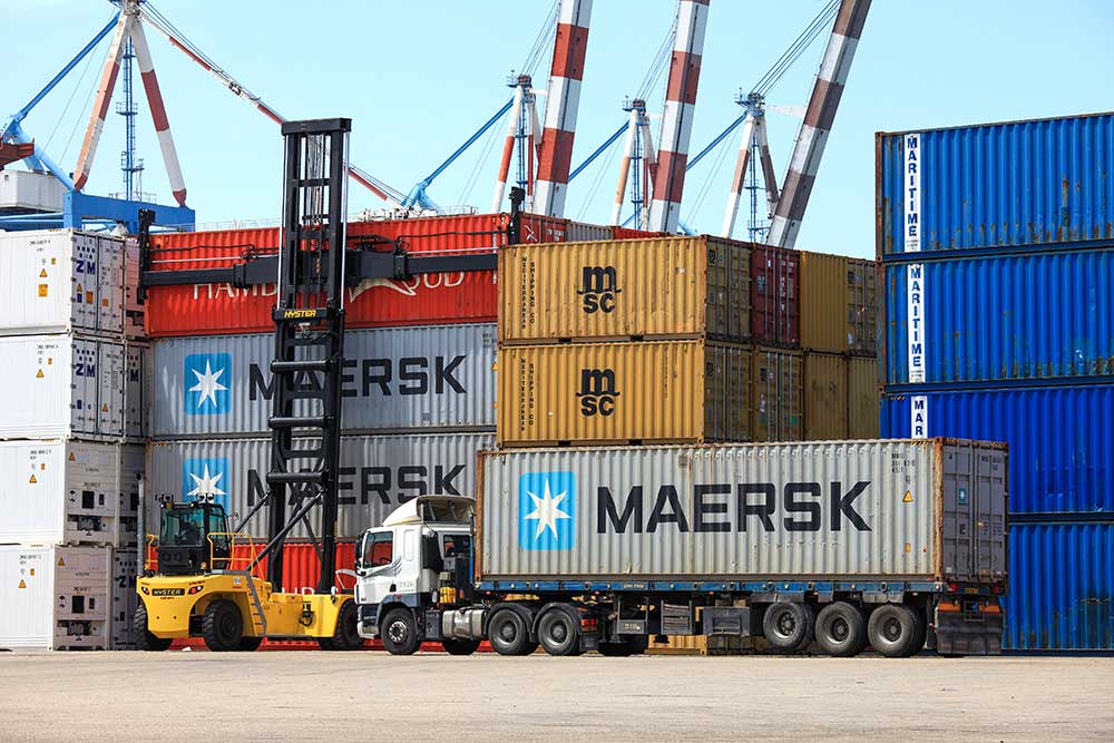 A shipping container getting loaded onto a truck