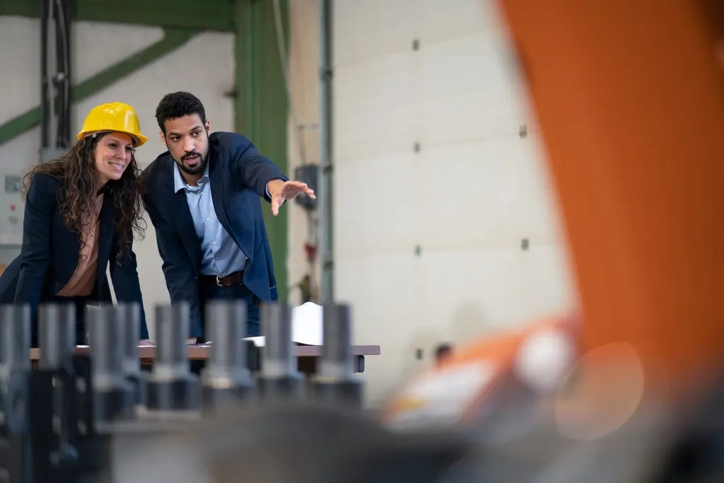 A man engineer showing machines to his collegue in industrial robotic factory.