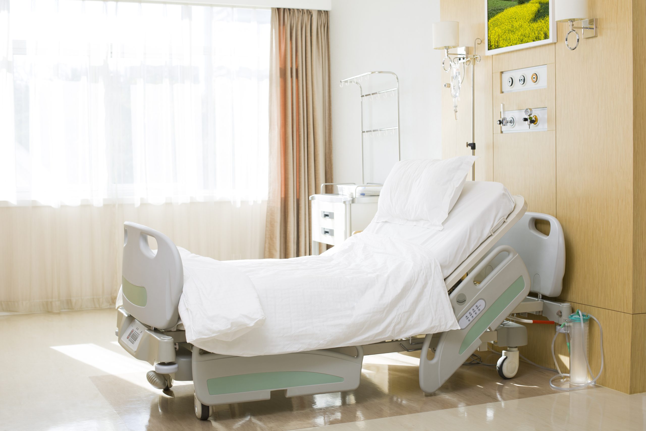Clean and well-lit hospital room with an adjustable medical bed and modern healthcare equipment.