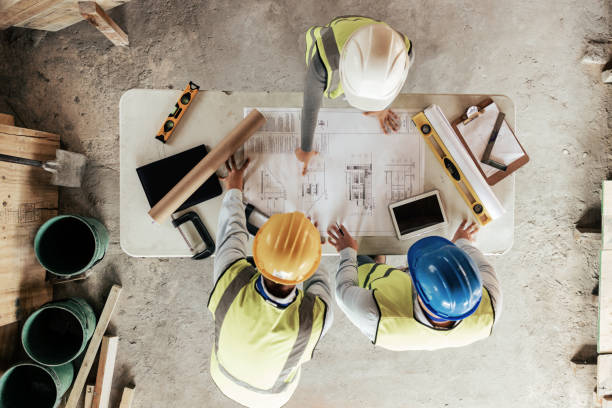 Construction site with workers reviewing blueprints, emphasizing precision and planning at an active job site.
