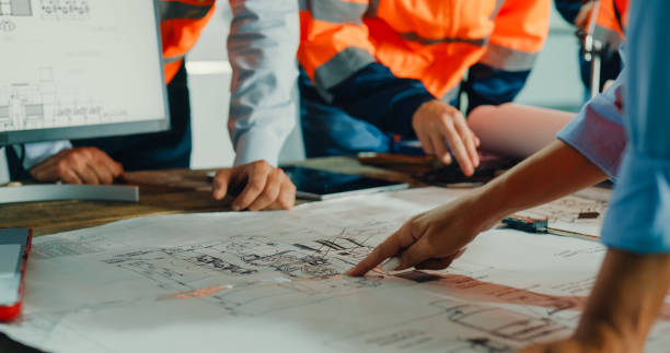 Construction professionals collaborate on architectural plans, symbolizing successful project execution through detailed planning and ADHECOGEN’s full-service support.