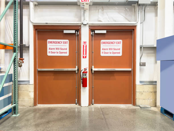 Emergency exit fire doors in a commercial facility, equipped with alarms and proper signage, highlighting the importance of compliant fire door installation.