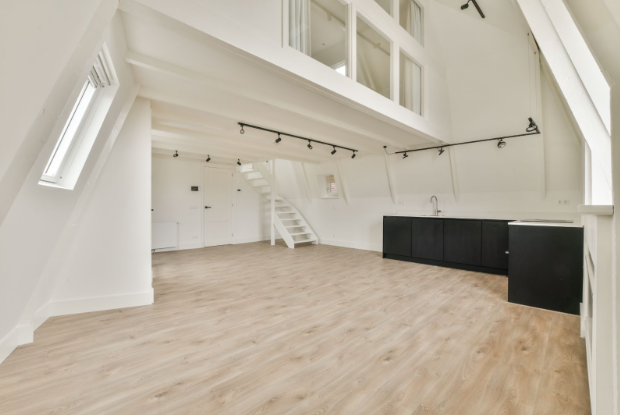 Bright modern loft with light oak LVT flooring, minimalist white walls, black kitchen cabinetry, and natural lighting.